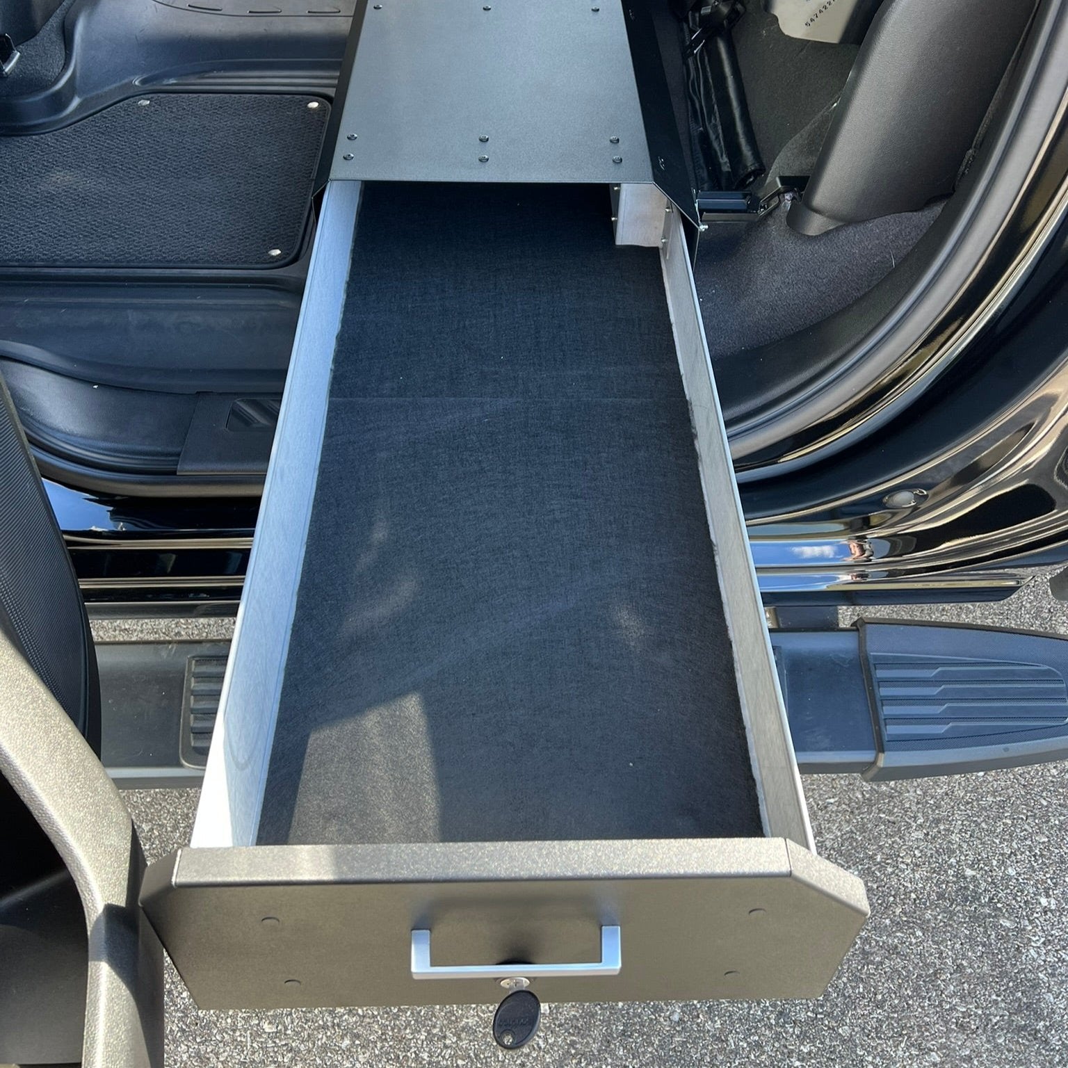 Chevy/GMC Gear-Guard Under-Seat Locker with the door open and installed in a truck. The locker is a high-quality powder coated galvanized steel.
