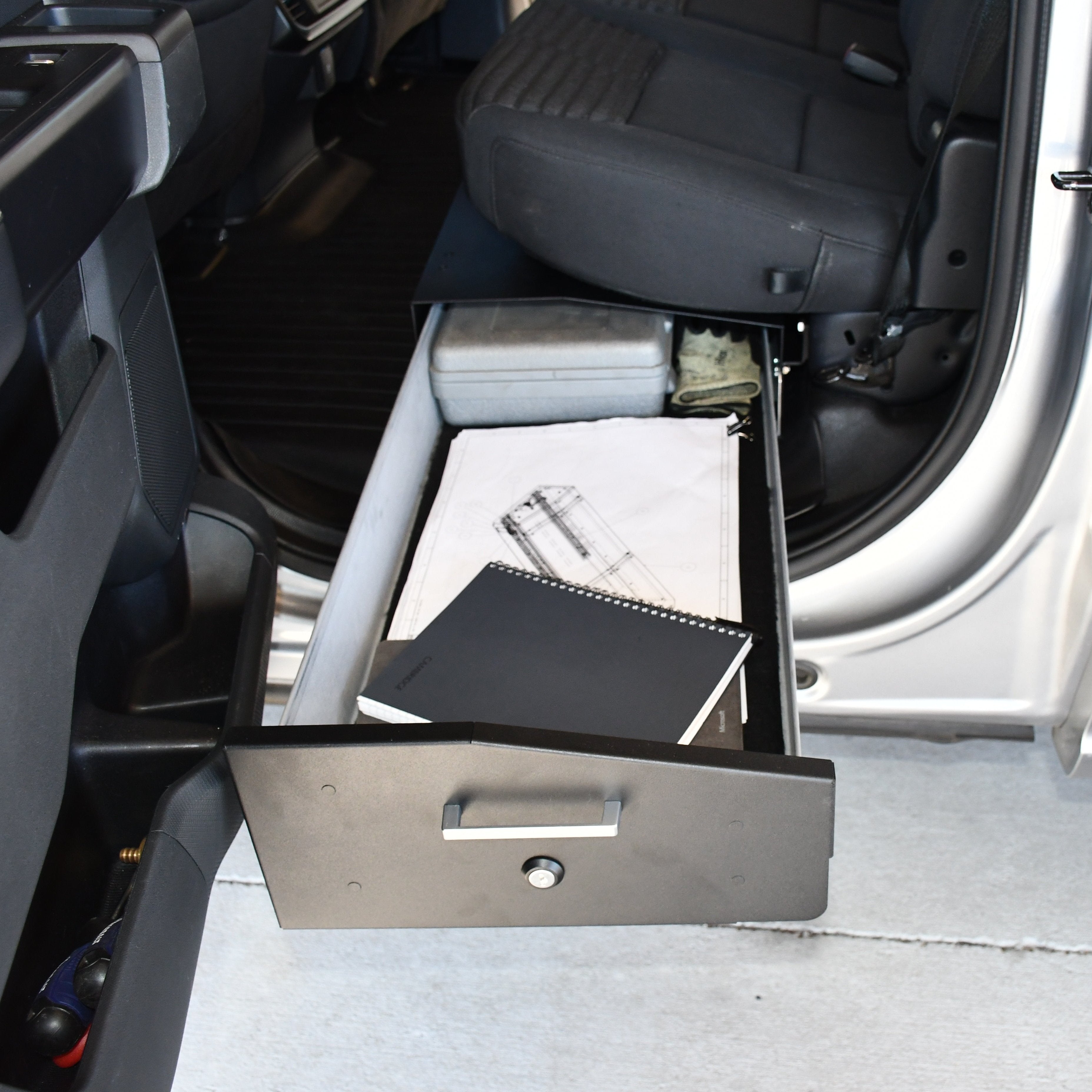 Ford Gear-Guard Under-Seat Locker with the door open and installed in the truck showing how it is used. The locker is a high-quality powder coated galvanized steel.