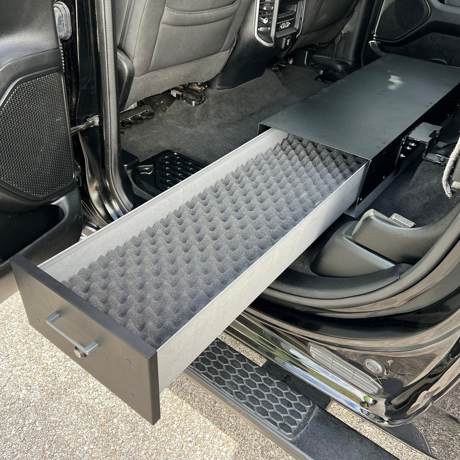 Ram Gear-Guard Under-Seat Locker with the door open and installed in a truck with the foam option. The locker is a high-quality powder coated galvanized steel.