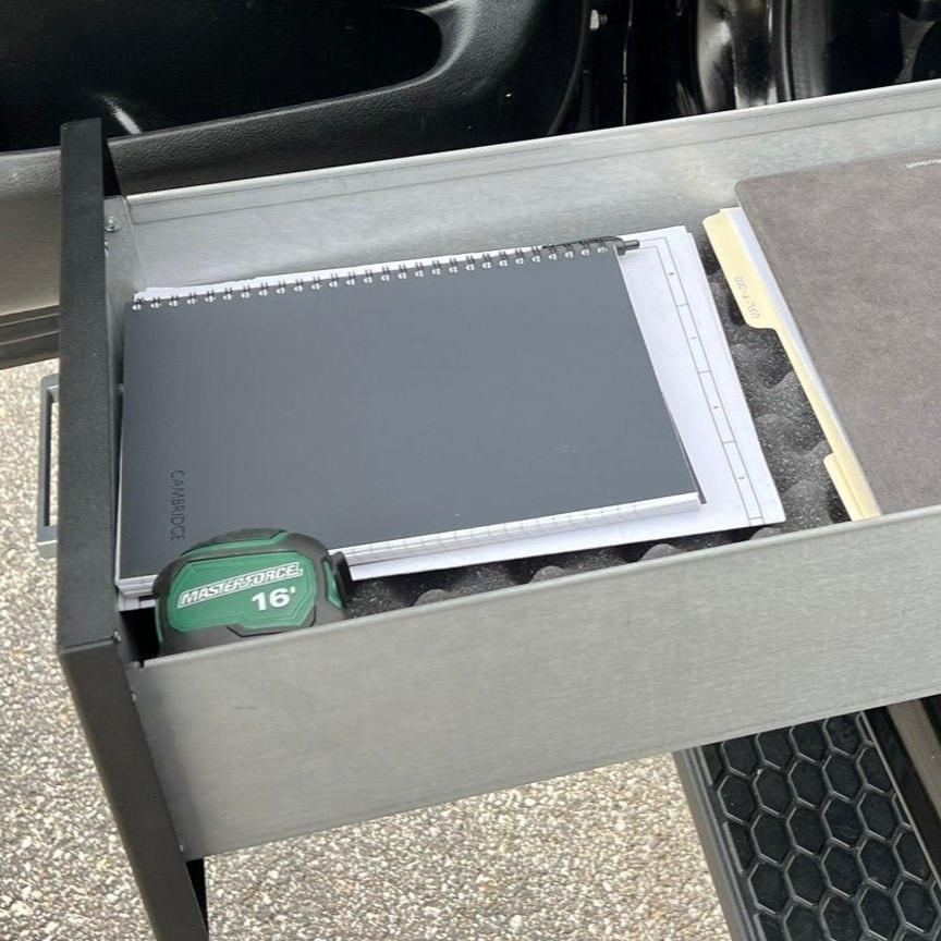 Chevy/GMC Gear-Guard Under-Seat Locker with the door open and installed in a trucking displaying the way it is used. The locker is a high-quality powder coated galvanized steel.